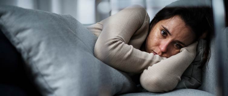 Young woman lying down with a pillow looking sad/depressed