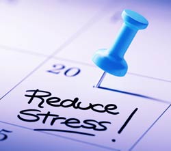 Calendar with push pin on the 20th day and Reduce Stress! penned in on date block.