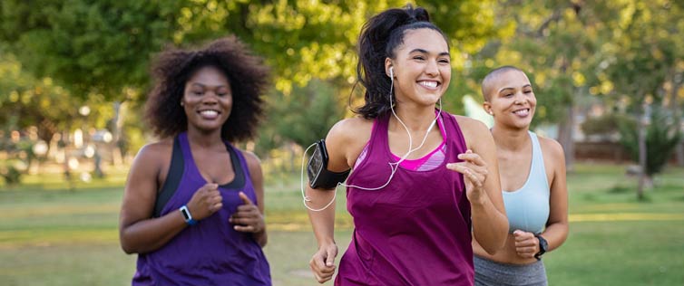 Three women smiling and jogging.