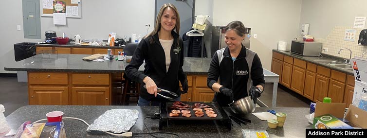 Two women cooking on a griddle.