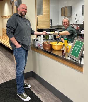 Man receiving breakfast plate from woman in kitchen.