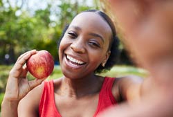 Woman in workout clothes holding an apple.