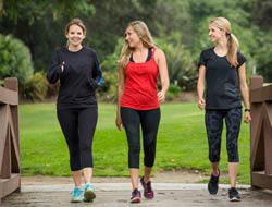 Three women in workout clothes walking across a bridge.