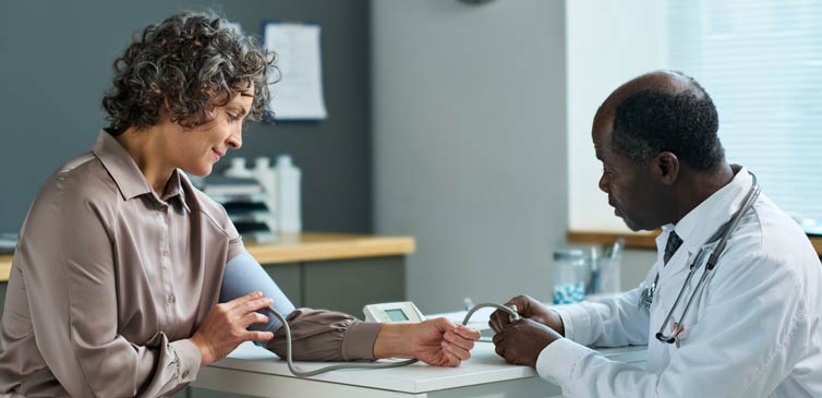 Nurse/doctor taking blood pressure of woman patient using a cuff.