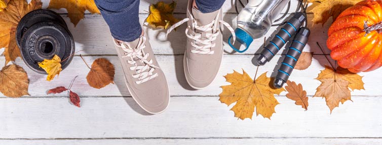 Fall leaves, a pumpkin, weights, jump rope, water bottle and two feet in athletic shoes/sneakers.