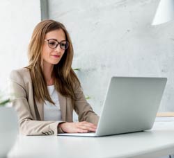 Young woman at a table working on a laptop.