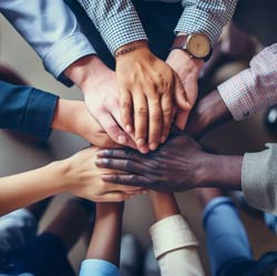 Group of 10 people’s hands piled on top of each other in the center.