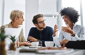 Three business people talking together in a meeting.