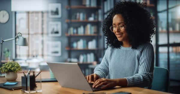 Young woman working on a laptop at a wooden table.