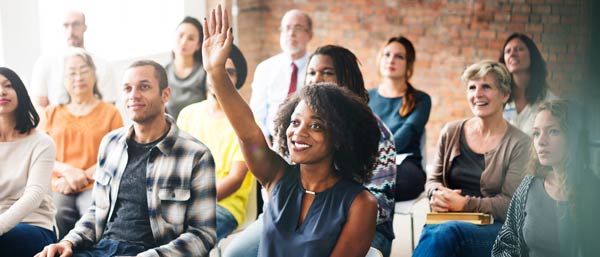 Businesswoman raising her hand to ask a question during a presentation.