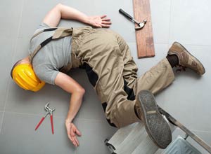 Worker splayed on the ground after falling (from a ladder) with tools around them on the floor.