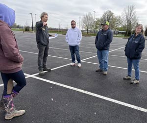 Paul talking with four employees in a parking lot.