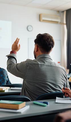 Training classroom with male attendee raising his hand to ask a question.