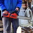 Person holding chainsaw, standing near a cut log.