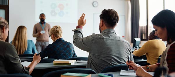 Training classroom with male attendee raising his hand to ask a question.