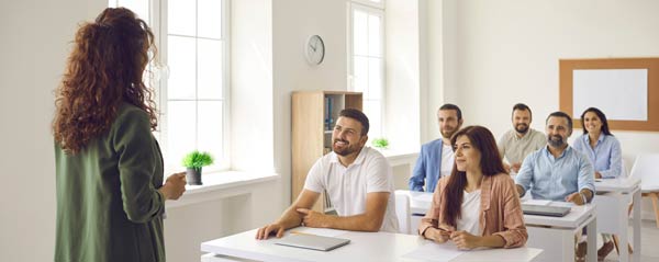 Female instructor facing class of young professionals.